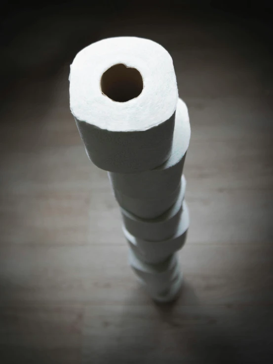 a stack of toilet paper sitting on top of a wooden floor, inspired by Sarah Lucas, paul barson, close-up photograph, malika favre, towering