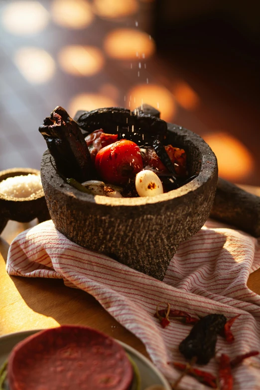 a bowl of food sitting on top of a wooden table, inspired by Ceferí Olivé, hurufiyya, mortar and pestle, spicy, iconic scene, charred