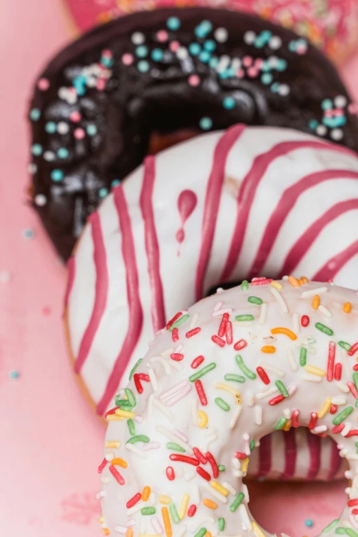 a number of doughnuts with sprinkles on a pink surface, a portrait, by Doug Ohlson, unsplash, kek, chocolate, 15081959 21121991 01012000 4k