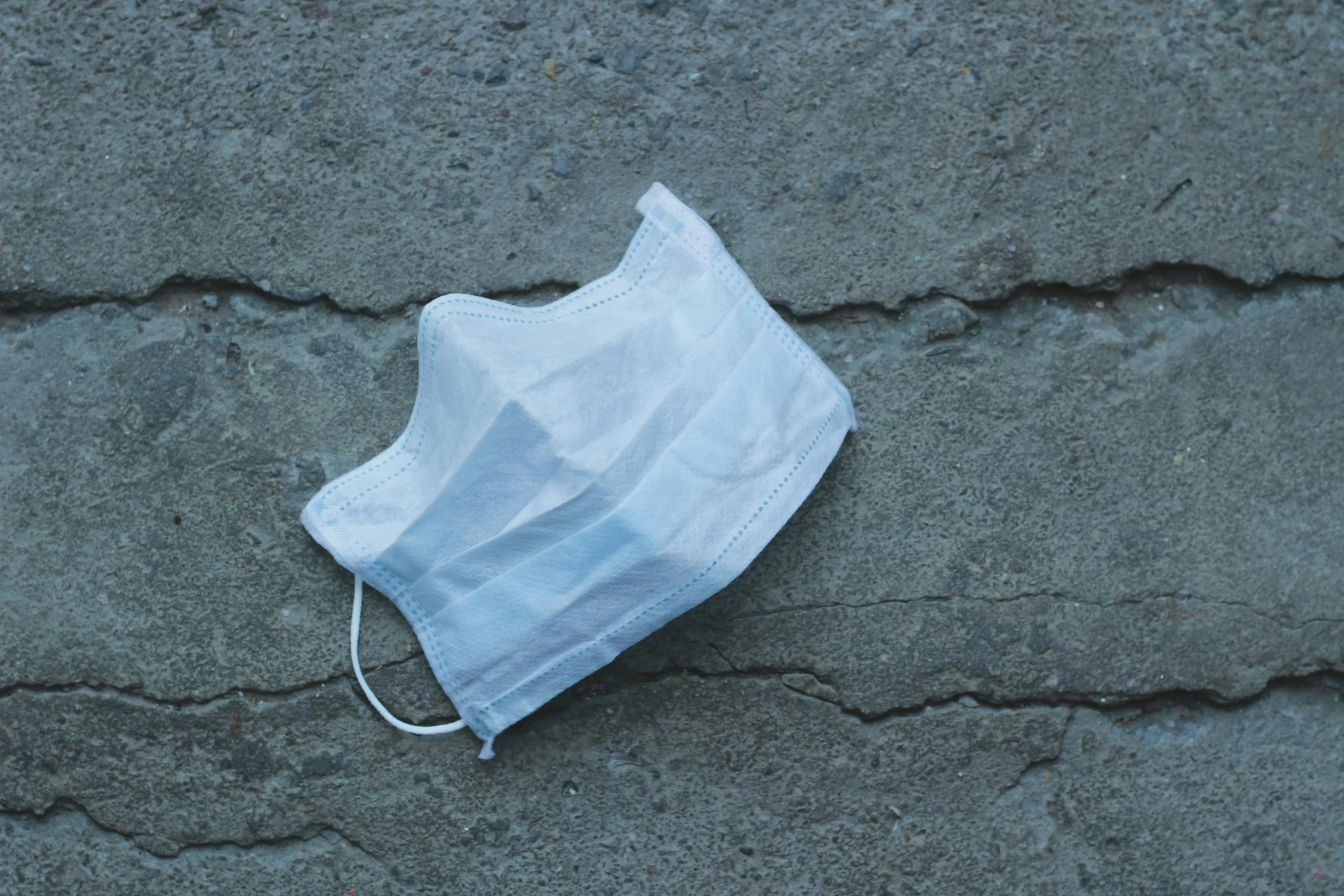 a white face mask laying on the ground, unsplash, faded worn, surgical supplies, ignant, rectangle