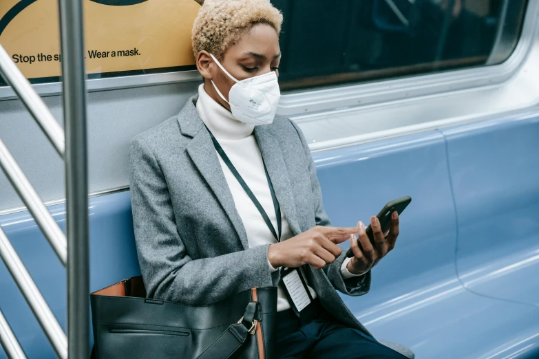 a woman sitting on a bus looking at her phone, trending on pexels, respirator, avatar image, black mask, 2 0 2 2 photo