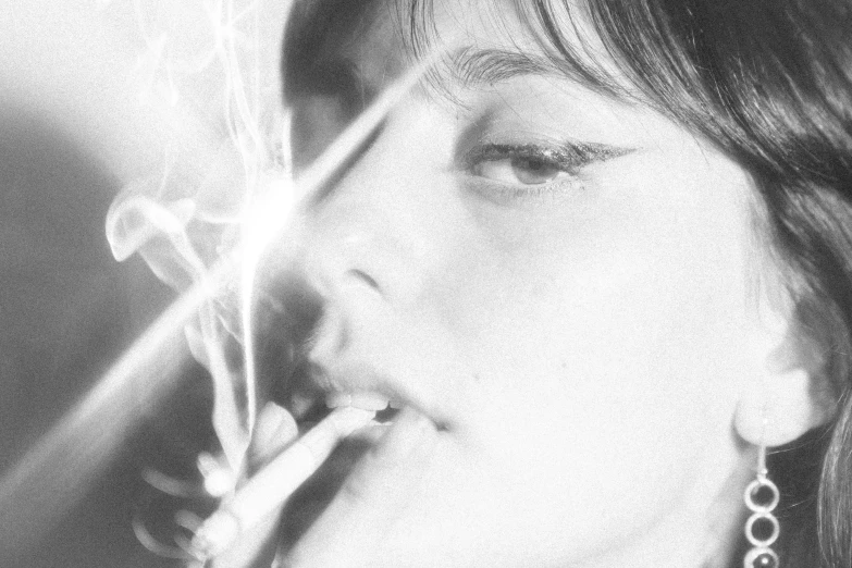 a black and white photo of a woman smoking a cigarette, by Shinoda Toko, tumblr, light effect. feminine, close-up shoot, amelie poulain, shining lights