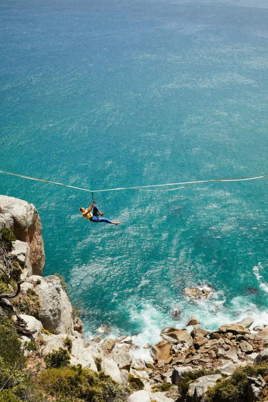 a person on a rope above a body of water, south african coast, flume, more intense, multiple stories