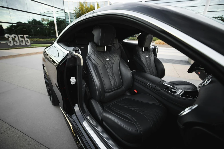 a black car parked in front of a building, leather interior, black textured, seated in royal ease, chrome and carbon