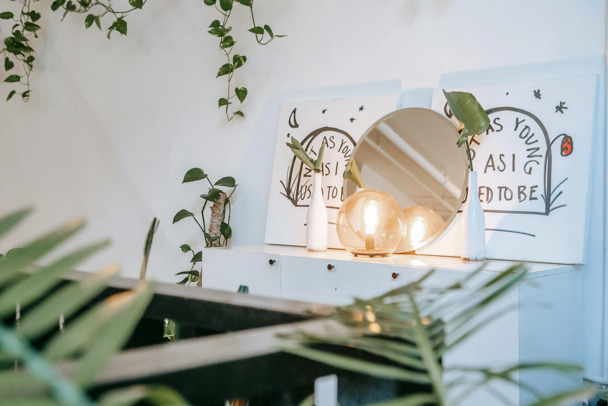 a mirror sitting on top of a dresser next to a plant, by Julia Pishtar, trending on unsplash, light and space, light bulbs, bright signage, home wicca scene, in a white boho style studio