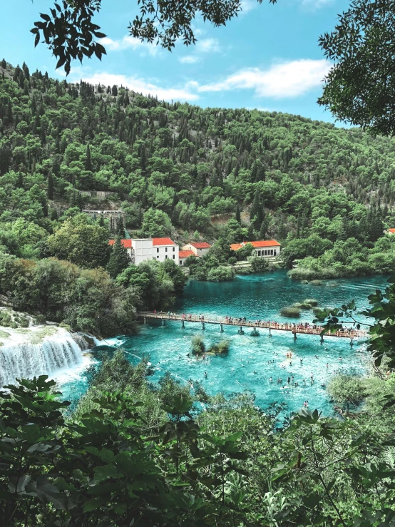 a large body of water surrounded by trees, by Kristian Zahrtmann, pexels contest winner, hurufiyya, white buildings with red roofs, multiple waterfalls, 🎀 🍓 🧚, square