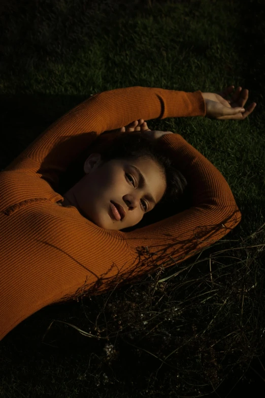 a woman laying on top of a lush green field, an album cover, inspired by Elsa Bleda, unsplash contest winner, orange body, portrait sophie mudd, dark mood, ignant