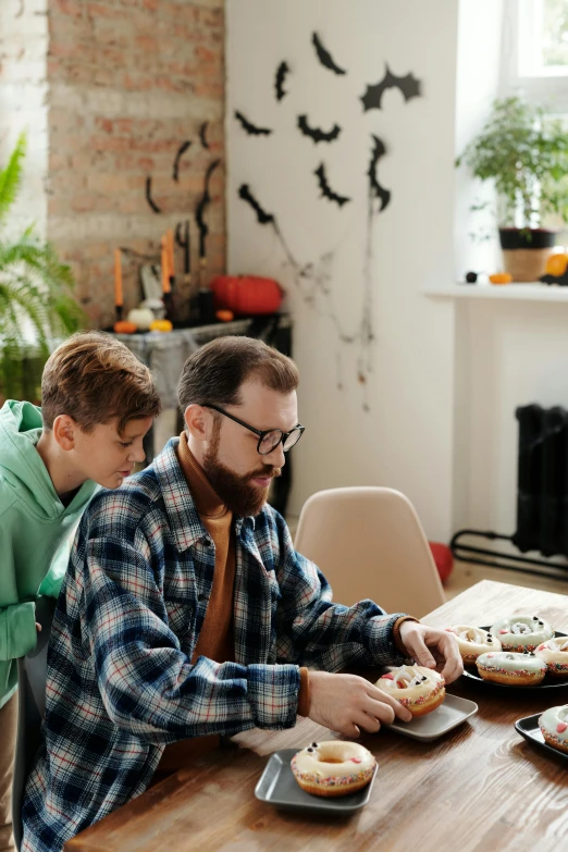 a man and a boy sitting at a table eating donuts, pexels contest winner, visual art, halloween decorations, hipster dad, apartment, caring fatherly wide forehead