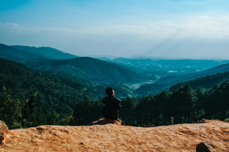 a person sitting on top of a large rock, trending on unsplash, korean countryside, profile image, multiple stories, velly distant forest