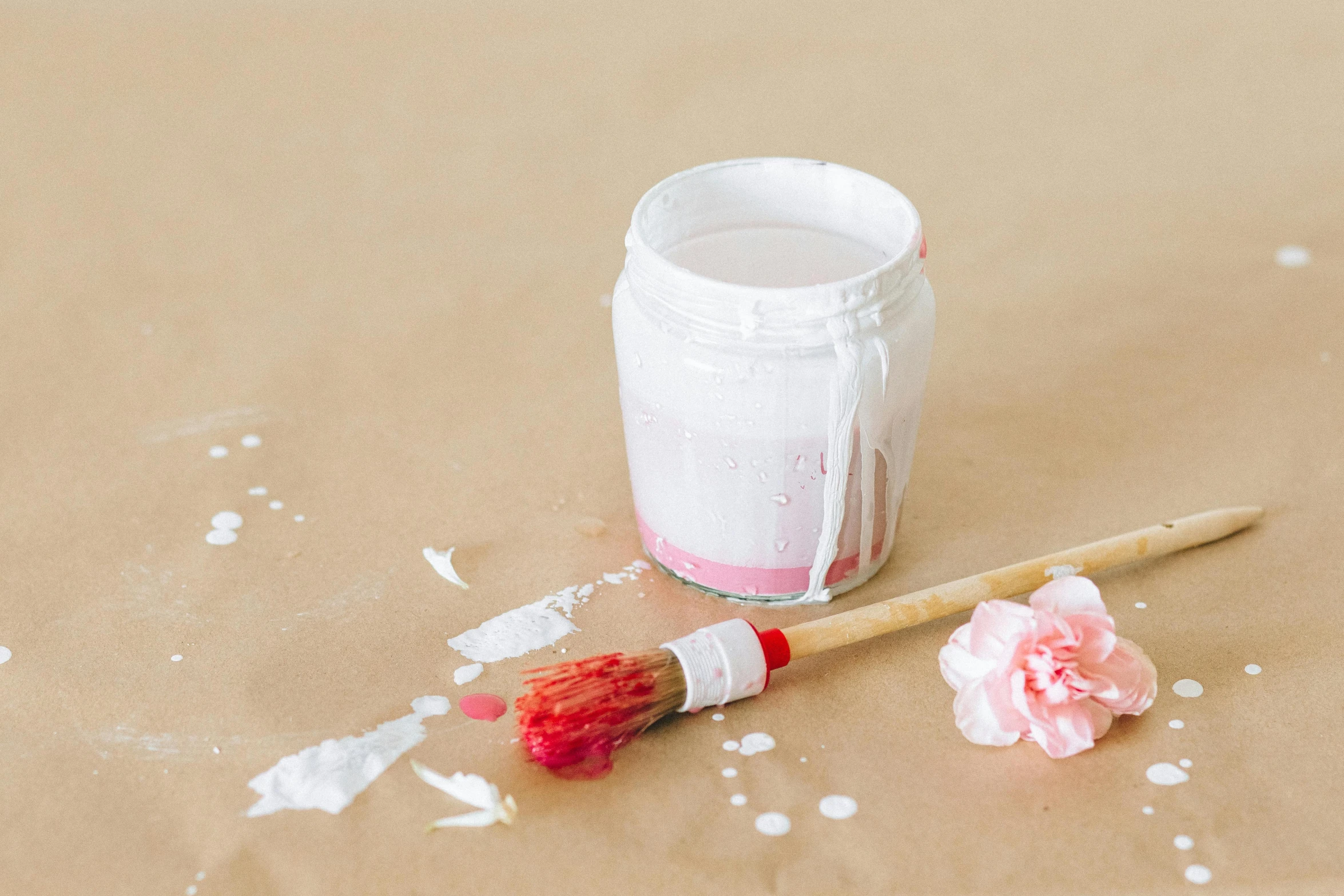 a paintbrush sitting on top of a table next to a jar of paint, inspired by Cy Twombly, trending on unsplash, white and pink cloth, paper craft, blooming effect, glossy white metal