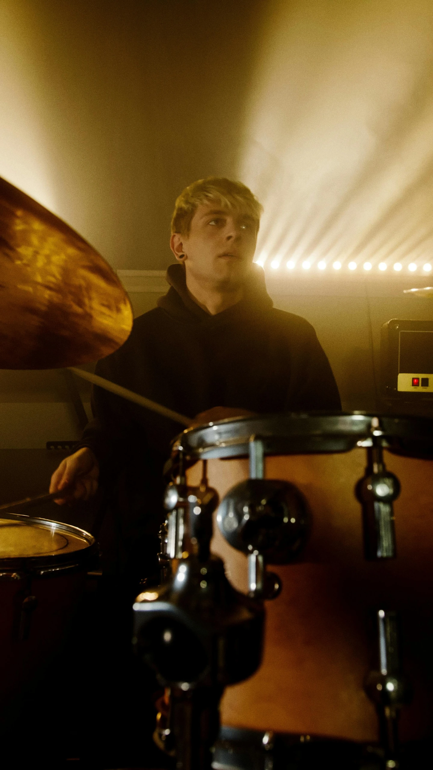 a man that is sitting in front of a drum, an album cover, inspired by Seb McKinnon, pexels, realism, still frame from a movie, young blonde boy fantasy thief, performing, mustard