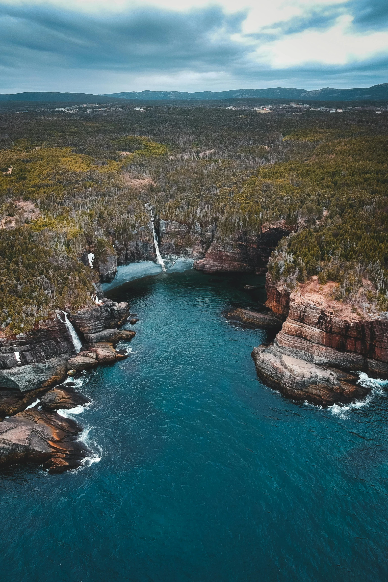 a large body of water surrounded by trees, by Peter Churcher, pexels contest winner, hurufiyya, coastal cliffs, multiple waterfalls, aerial photograph, “ iron bark