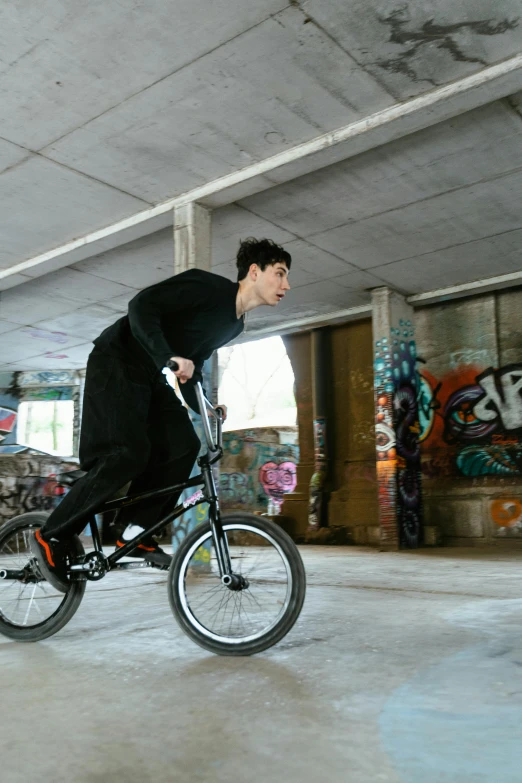 a man riding a bike in a parking garage, inspired by Seb McKinnon, in an action pose, declan mckenna, action sports, promo image