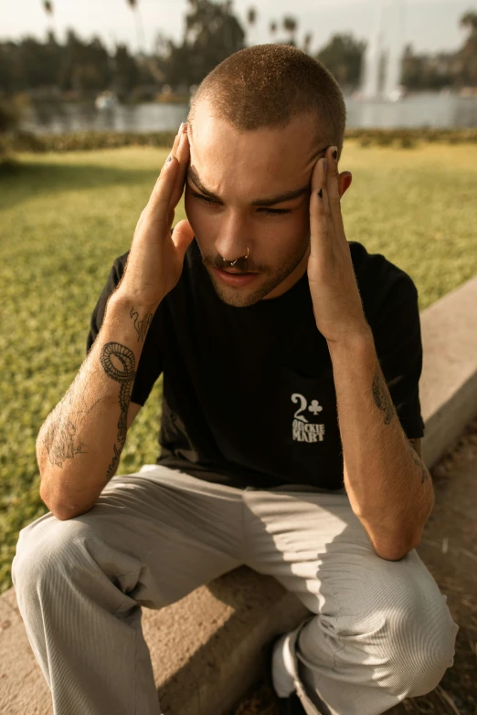 a man sitting on a curb with his head in his hands, trending on pexels, embroidered shirt, non binary model, black t shirt, worry