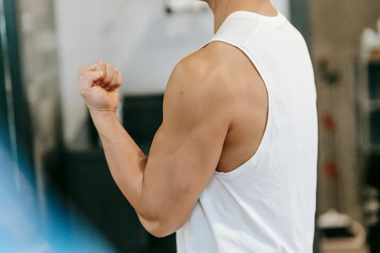 a man in a white tank top holding a tennis racquet, a cartoon, trending on pexels, showing off biceps, manuka, local gym, no - text no - logo