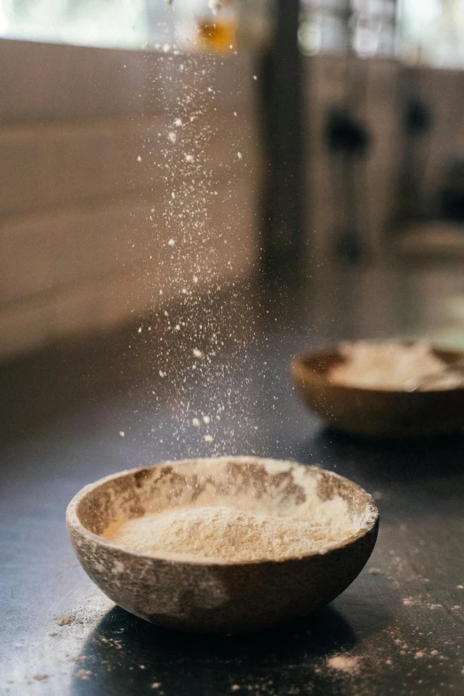 a couple of bowls sitting on top of a counter, by Ruth Simpson, trending on unsplash, flour dust flying, glittering light, ignant, pastry