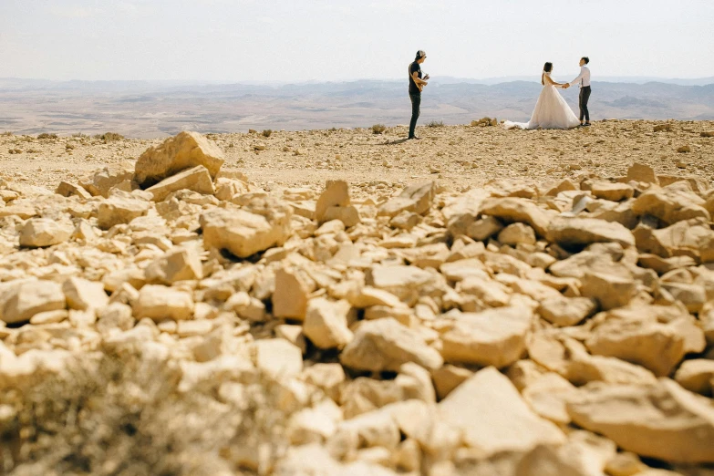 a couple of people standing on top of a rocky hill, pexels contest winner, les nabis, israel, wedding, gravel and scree ground, three views