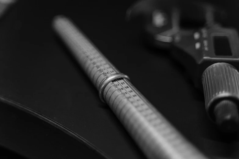 a pen sitting on top of a table next to a ruler, a macro photograph, by Mathias Kollros, cinestill hasselblad 2 0 0 mm, wrench, platinum jewellery, depth of field : - 2