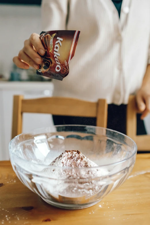 a person pouring something into a bowl on a table, fuji choco, burst of powders, medium, in a kitchen