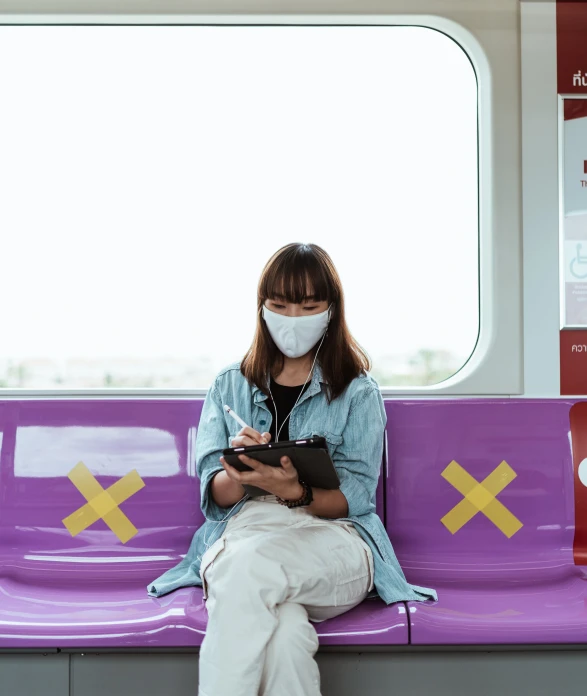 a woman sitting on a train looking at her phone, by Emma Andijewska, pexels contest winner, graffiti, medical mask, woman holding sign, asian human, purple