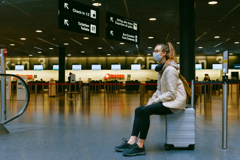 a woman sitting on top of a suitcase in an airport, pexels contest winner, happening, people are wearing masks, in australia, avatar image, sitting on bench