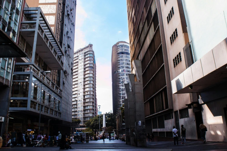 a city street filled with lots of tall buildings, inspired by Ned M. Seidler, pexels contest winner, modernism, buildings carved out of stone, on a hot australian day, avenida paulista, half turned around