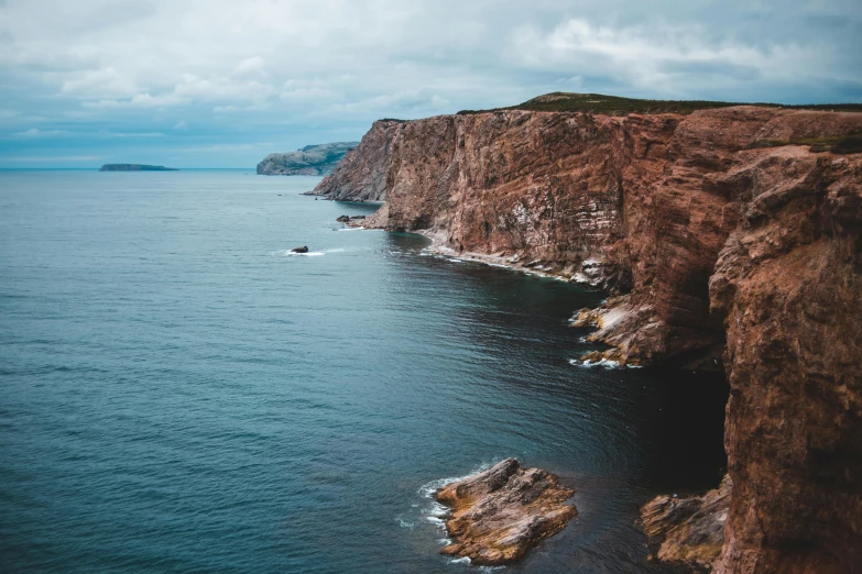 a large body of water next to a cliff, pexels contest winner, les nabis, coastal cliffs, brown, thumbnail, high quality image”