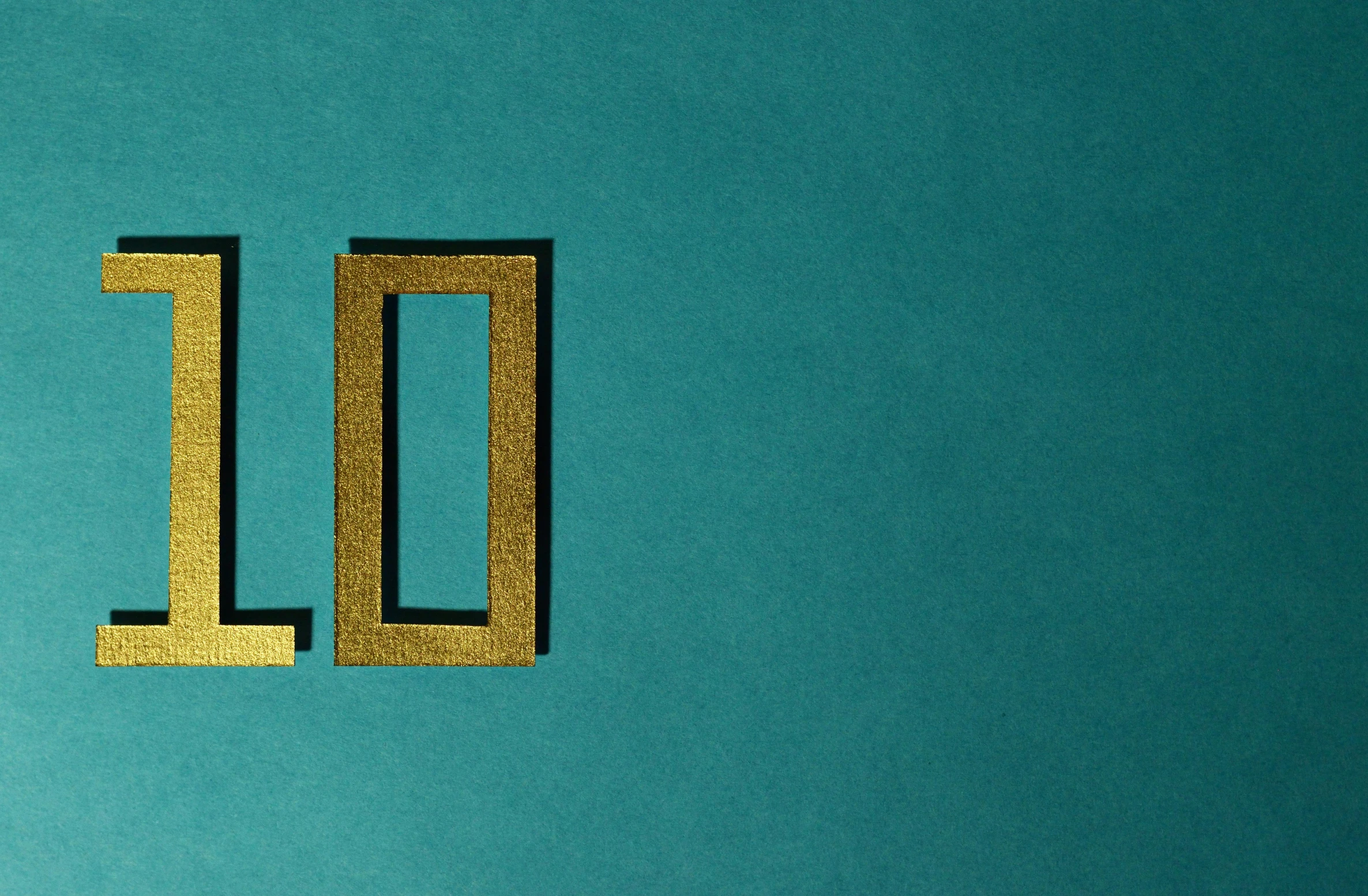a close up of a number on a blue surface, an album cover, inspired by Zsolt Bodoni, trending on unsplash, international typographic style, gold and teal color scheme, yolo, hello, no - text no - logo