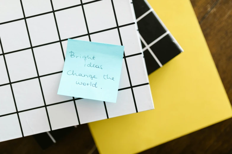 a sticky note sitting on top of a pile of books, trending on pexels, grid arrangement, hopeful and bright, black squares on 4 corners, thumbnail