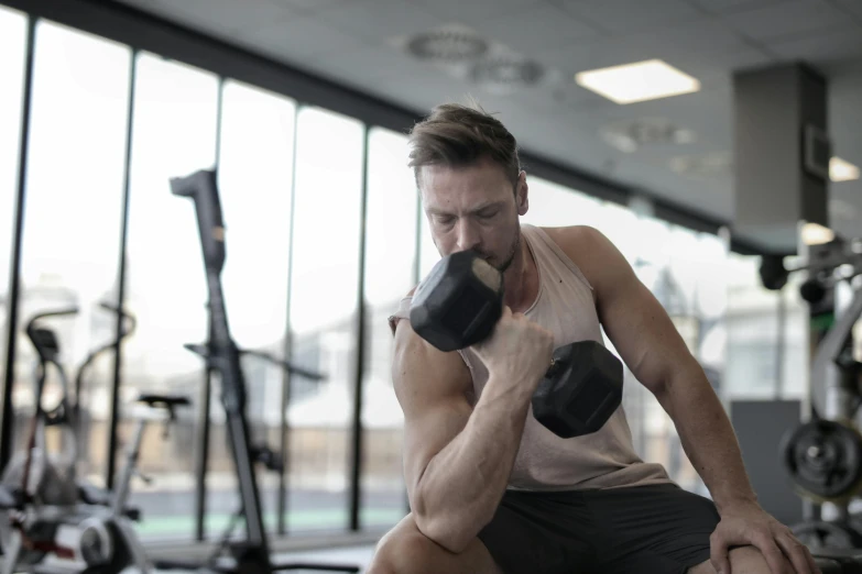 a man holding a pair of dumbbells in a gym, by Dan Luvisi, pexels contest winner, lachlan bailey, profile image, attractive face and body, skies behind