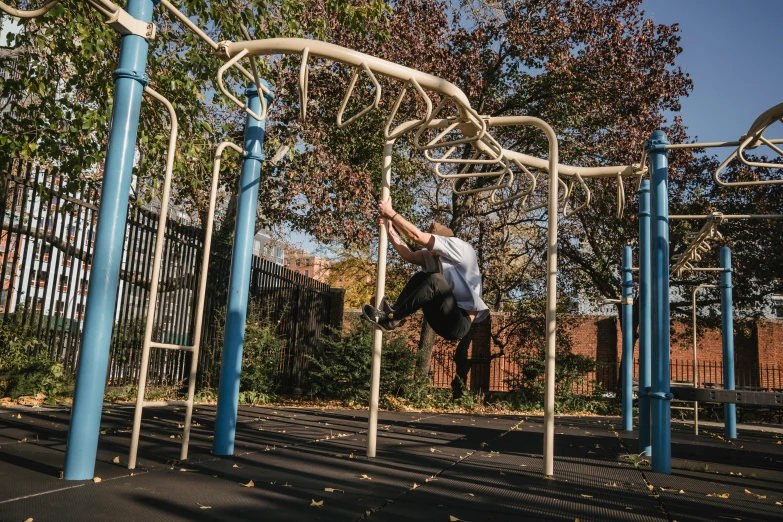 a man doing a trick on a monkey bars, by Matt Stewart, steel archways, photograph taken in 2 0 2 0, gnarled, urban playground