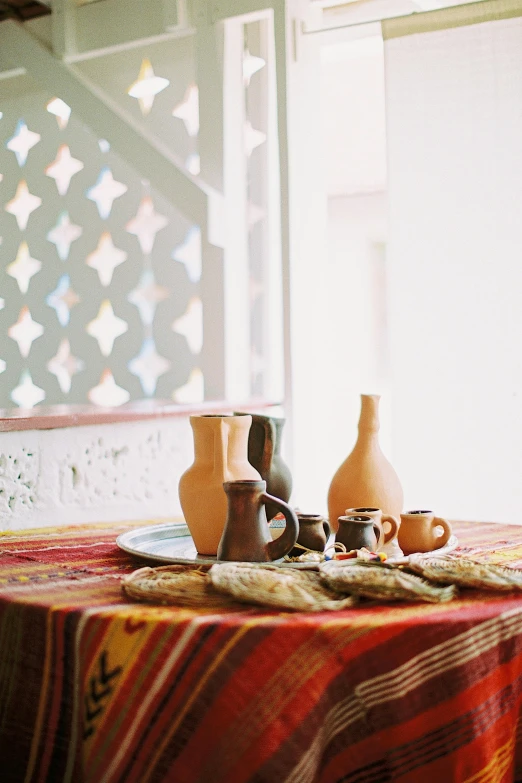 a table that has some vases on it, a still life, inspired by Riad Beyrouti, unsplash, dau-al-set, traditional clothes, brown, taken with kodak portra, bay area