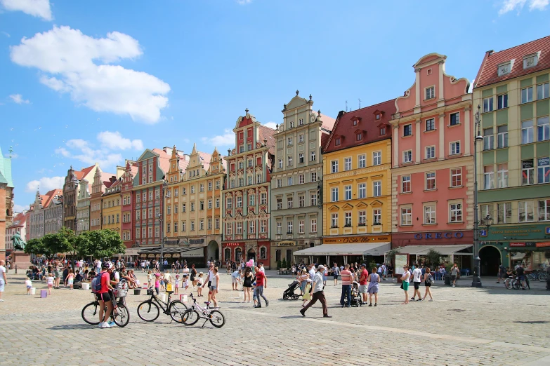 a group of people walking down a street next to tall buildings, by Adam Marczyński, pexels contest winner, renaissance, colorful houses, in a city square, slide show, bright summer day