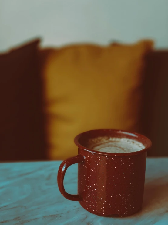 a close up of a cup of coffee on a table, inspired by Elsa Bleda, red and brown color scheme, throw pillows, profile image, lo - fi