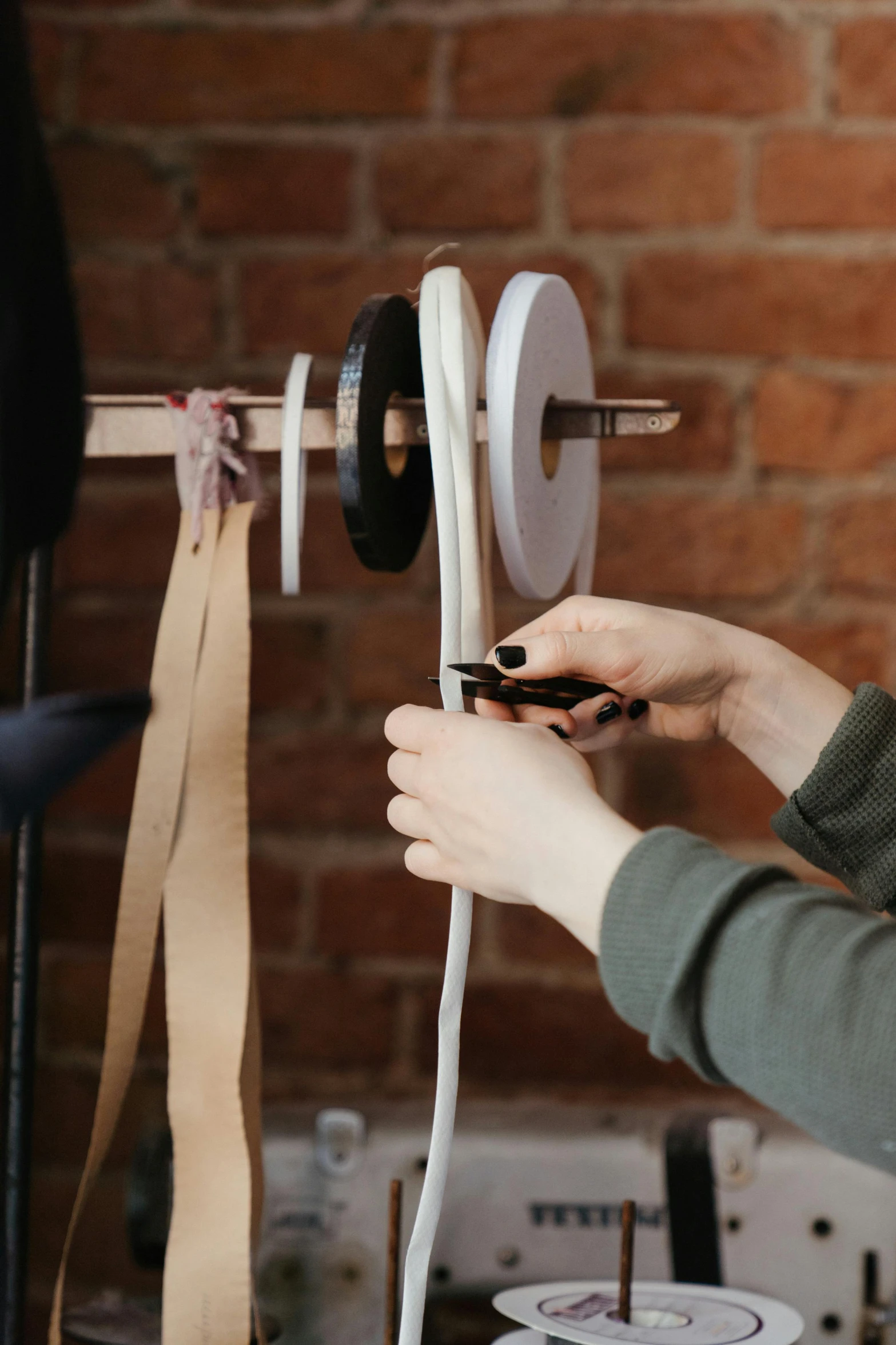 a woman working on a sewing machine in front of a brick wall, leather straps, paper craft, dezeen showroom, close up photograph