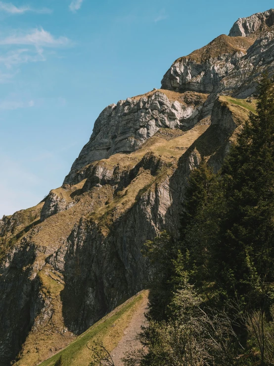 a person standing on a path in front of a mountain, les nabis, extremely detailed rocky crag, unsplash 4k, switzerland, 3/4 view from below