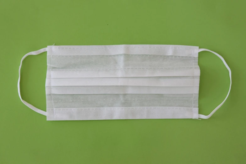 a white face mask on a green background, obi strip, ultra clear material, surgical impliments, on a pale background