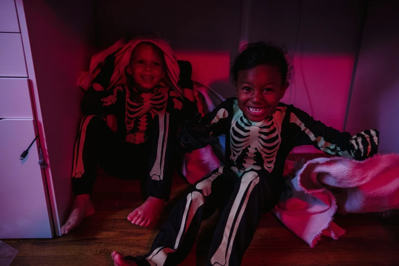 two children in halloween costumes sitting on the floor, by Helen Stevenson, pexels contest winner, vanitas, glowing bones, dark skinned, in the bedroom at a sleepover, slide show