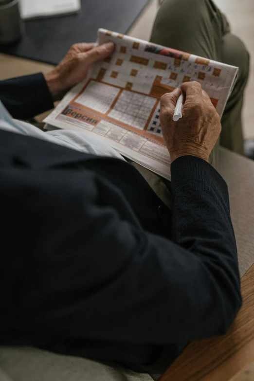 a man sitting on a couch reading a newspaper, a picture, by Tobias Stimmer, pexels contest winner, private press, puzzle, japanese, close-up photograph, lawther sit at table playing dnd