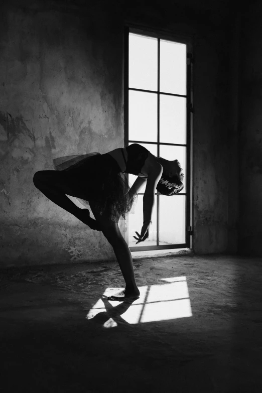 a black and white photo of a woman doing a handstand, a black and white photo, by Elizabeth Polunin, pexels contest winner, arabesque, leaning against the window, light behind, andrey gordeev, leaning on door