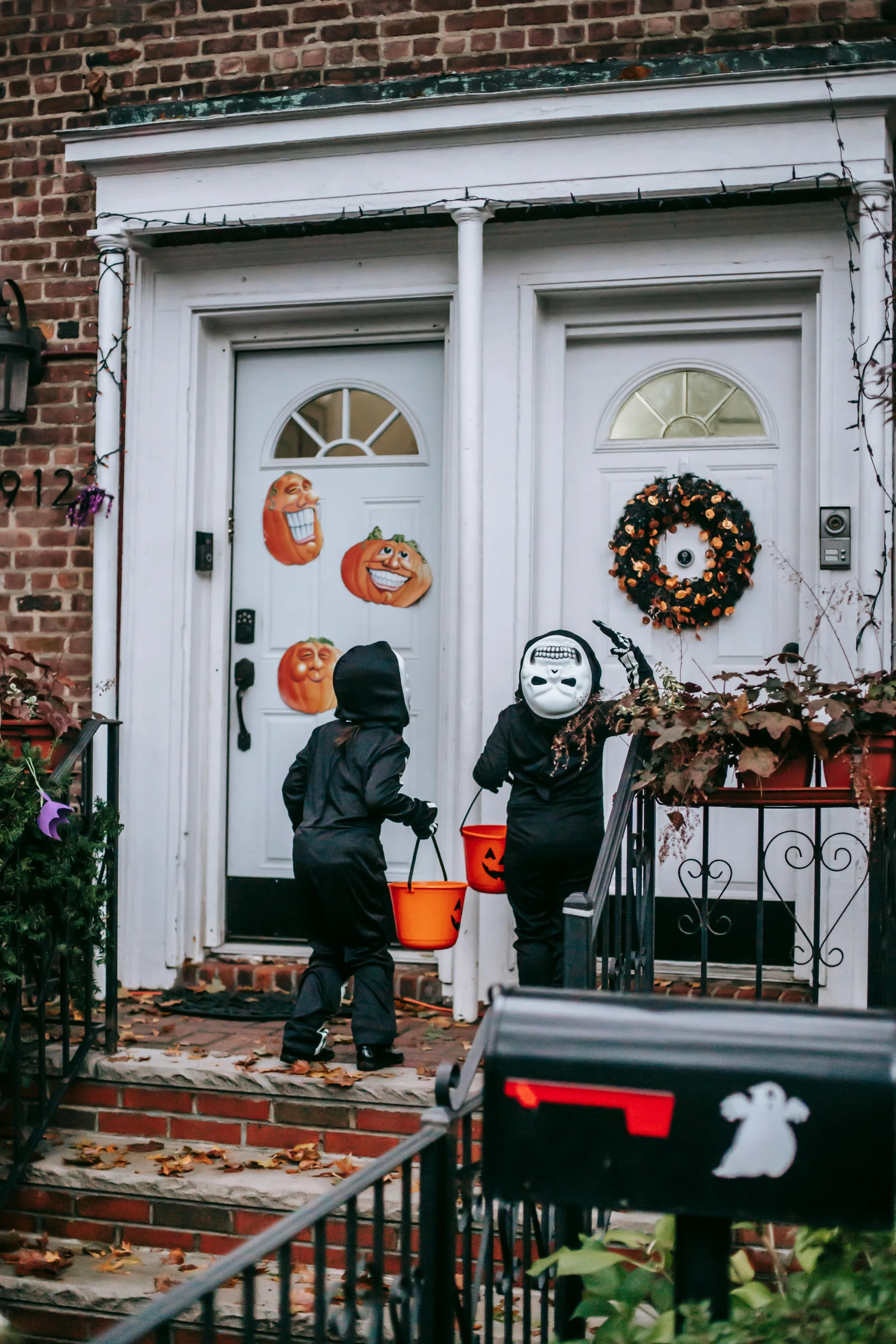 a couple of people that are standing in front of a house, halloween decorations, doors, kids playing, profile image