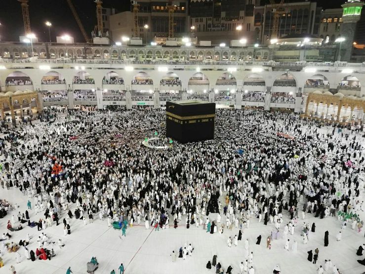 a large crowd of people standing around a building, a picture, by Meredith Dillman, pexels, hurufiyya, mecca, inside a grand, wearing white cloths, people on the ground