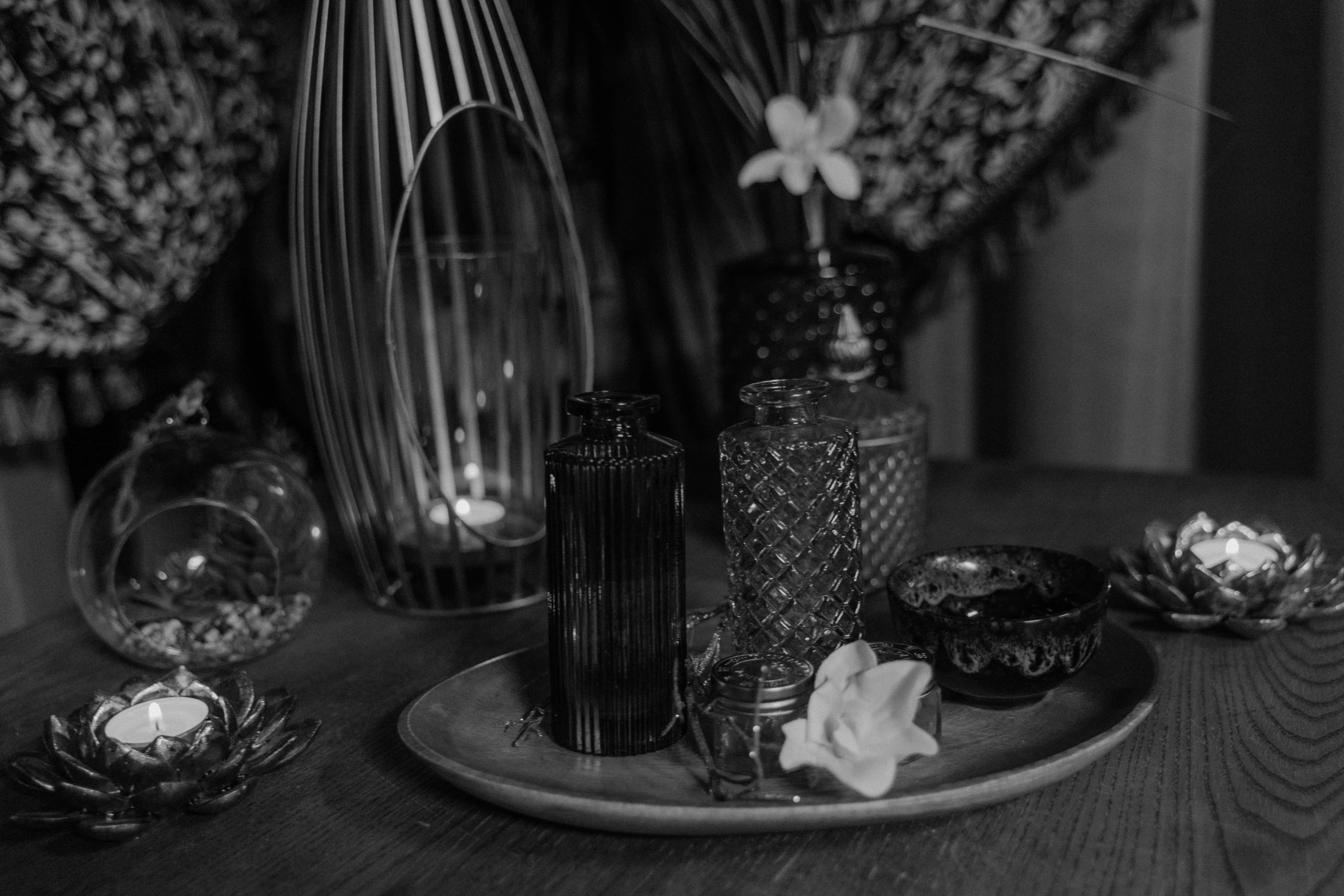 a wooden table topped with vases filled with flowers, a black and white photo, pexels, renaissance, dark and moody aesthetic, high details photo, detailed product photo, incense