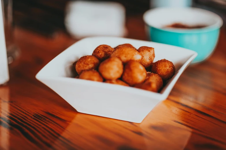a bowl of food sitting on top of a wooden table, puffballs, deep fried, profile image, local foods