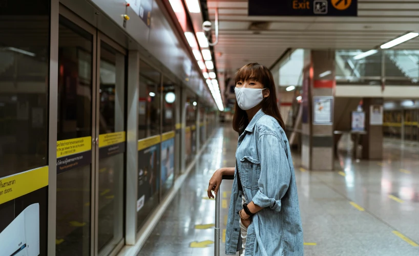 a woman wearing a face mask and holding a suitcase, pexels contest winner, hyperrealism, underground metro, chinese, avatar image, woman holding sign