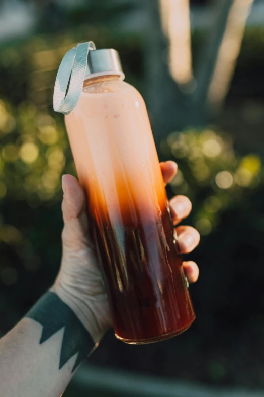 a person holding a water bottle in their hand, two tone dye, manuka, bloody sunset, made of glazed