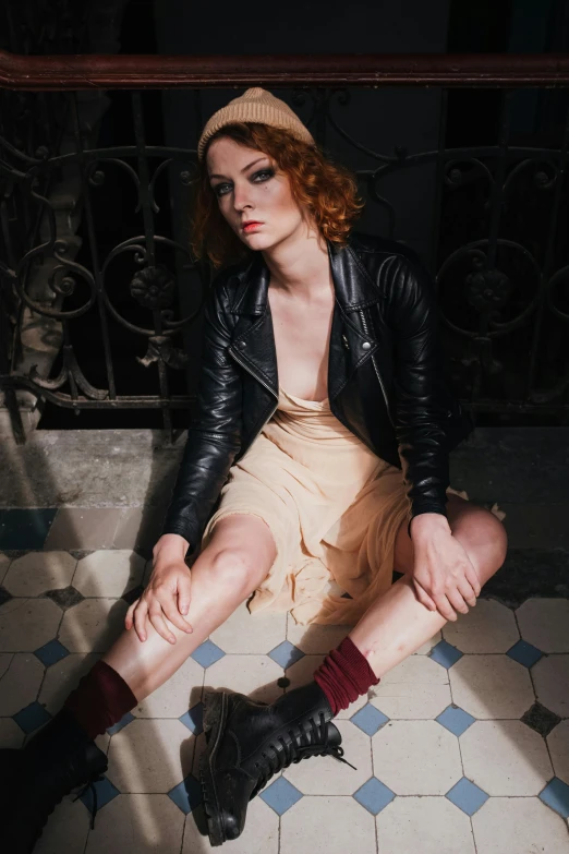 a woman is sitting on a tiled floor, inspired by Nan Goldin, trending on pexels, renaissance, leather clothing, wild ginger hair, young handsome pale roma, promotional image