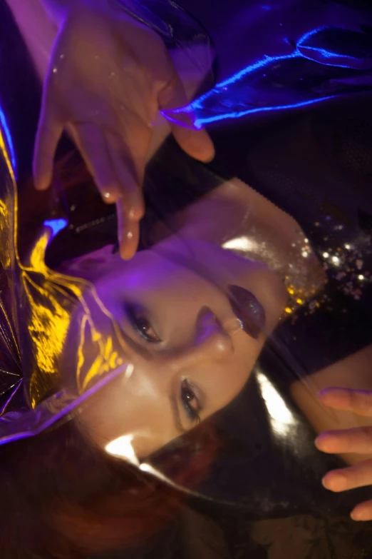 a close up of a person wearing a costume, an album cover, inspired by hajime sorayama, holography, kiko mizuhara, gold and purple, upside down, reflection lumen mapping
