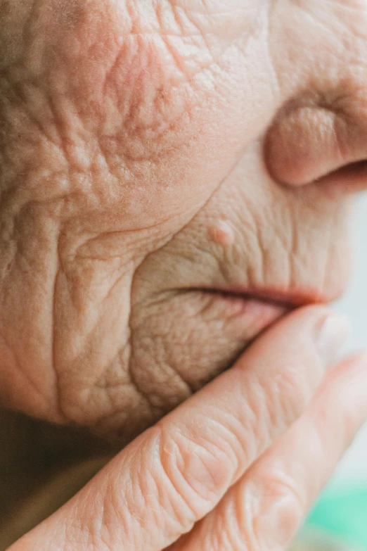 a close up of a person holding their hand to their face, old skin, licking out, particulate, with a pointed chin