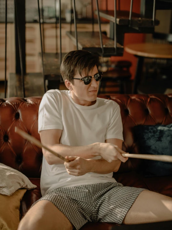 a man sitting on a couch playing drums, trending on reddit, round glasses potter, nathan fillion, cinematic outfit photo, profile image